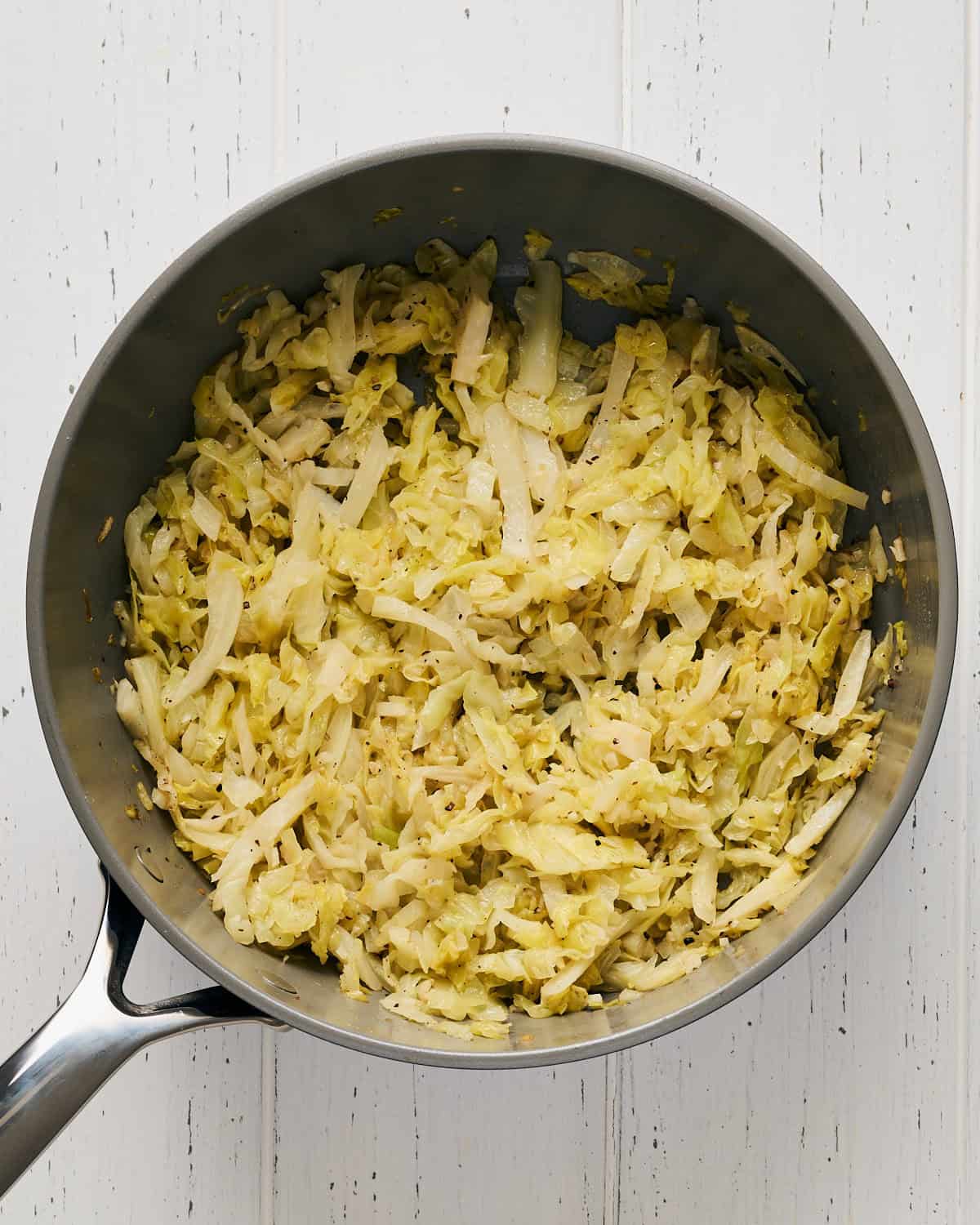 Cooking cabbage in a saucepan with garlic and olive oil.