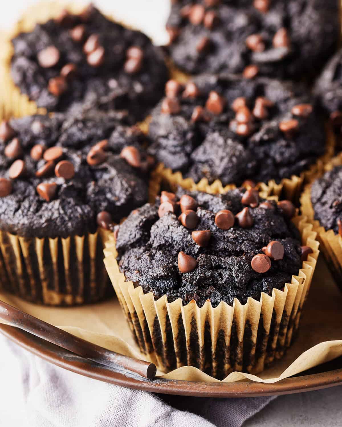 A round tray with seven vegan chocolate sweet potato muffins on parchment paper.