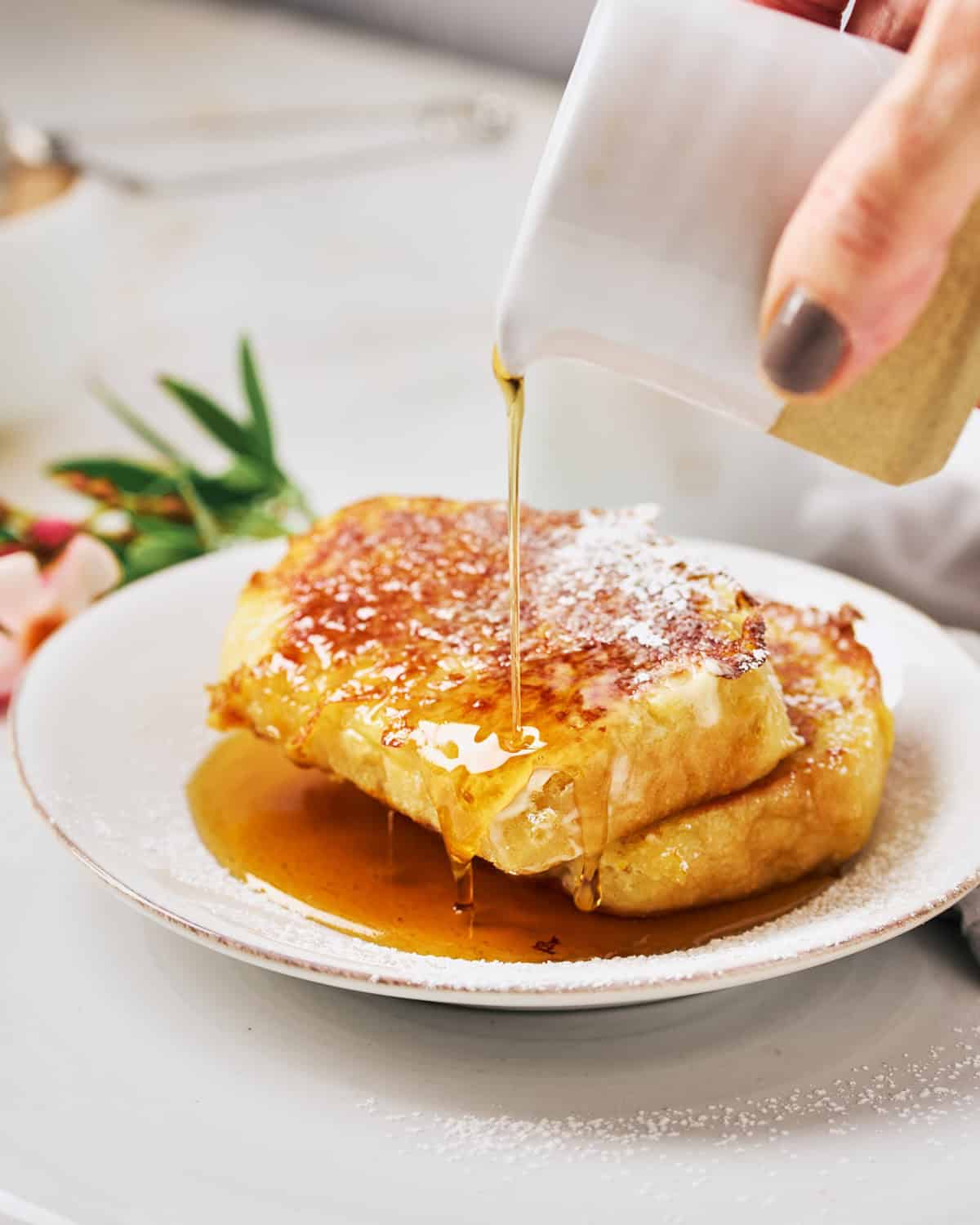 Pouring maple syrup on plant-based JUST Egg French Toast with Grand Marnier.