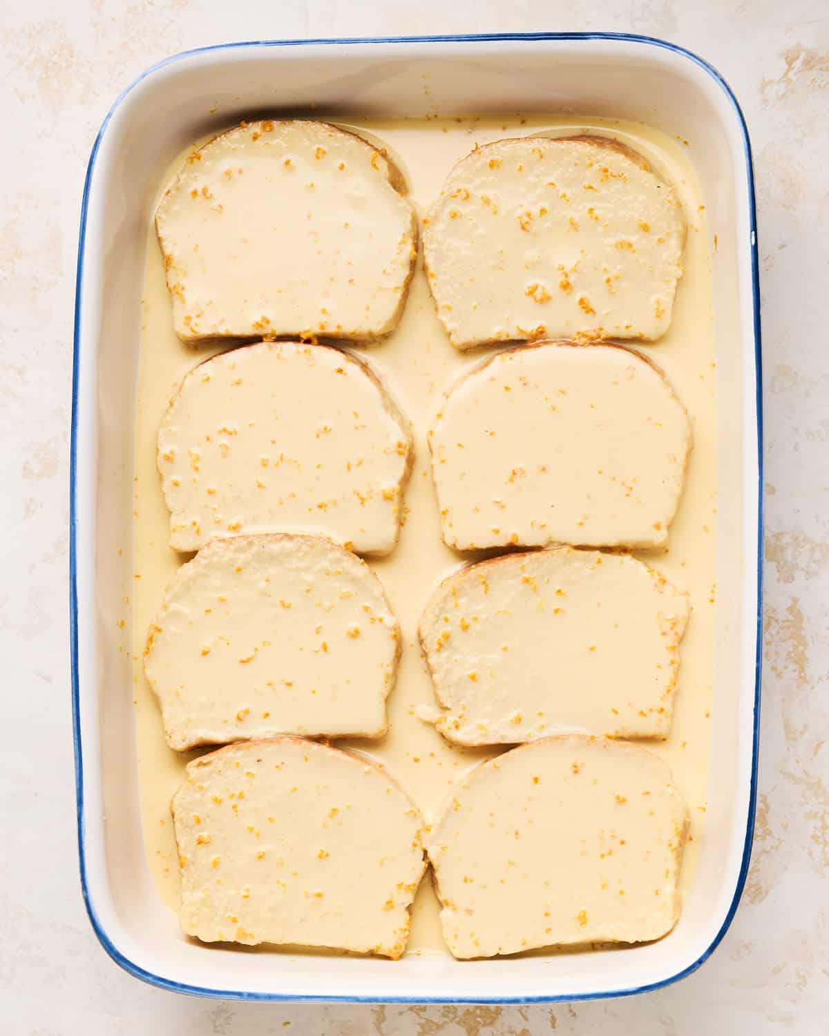 Soaking slices of vegan brioche in JUST Egg custard in a baking dish.