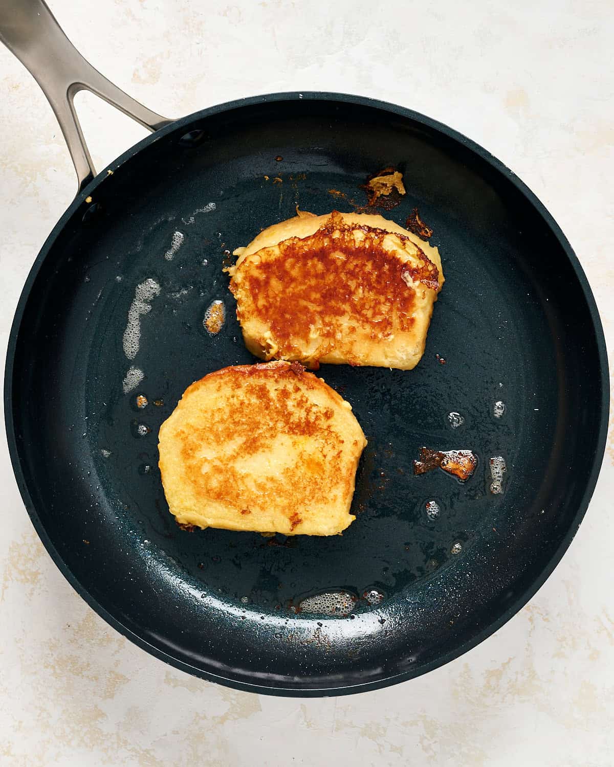 Two pieces of French toast in a skillet.