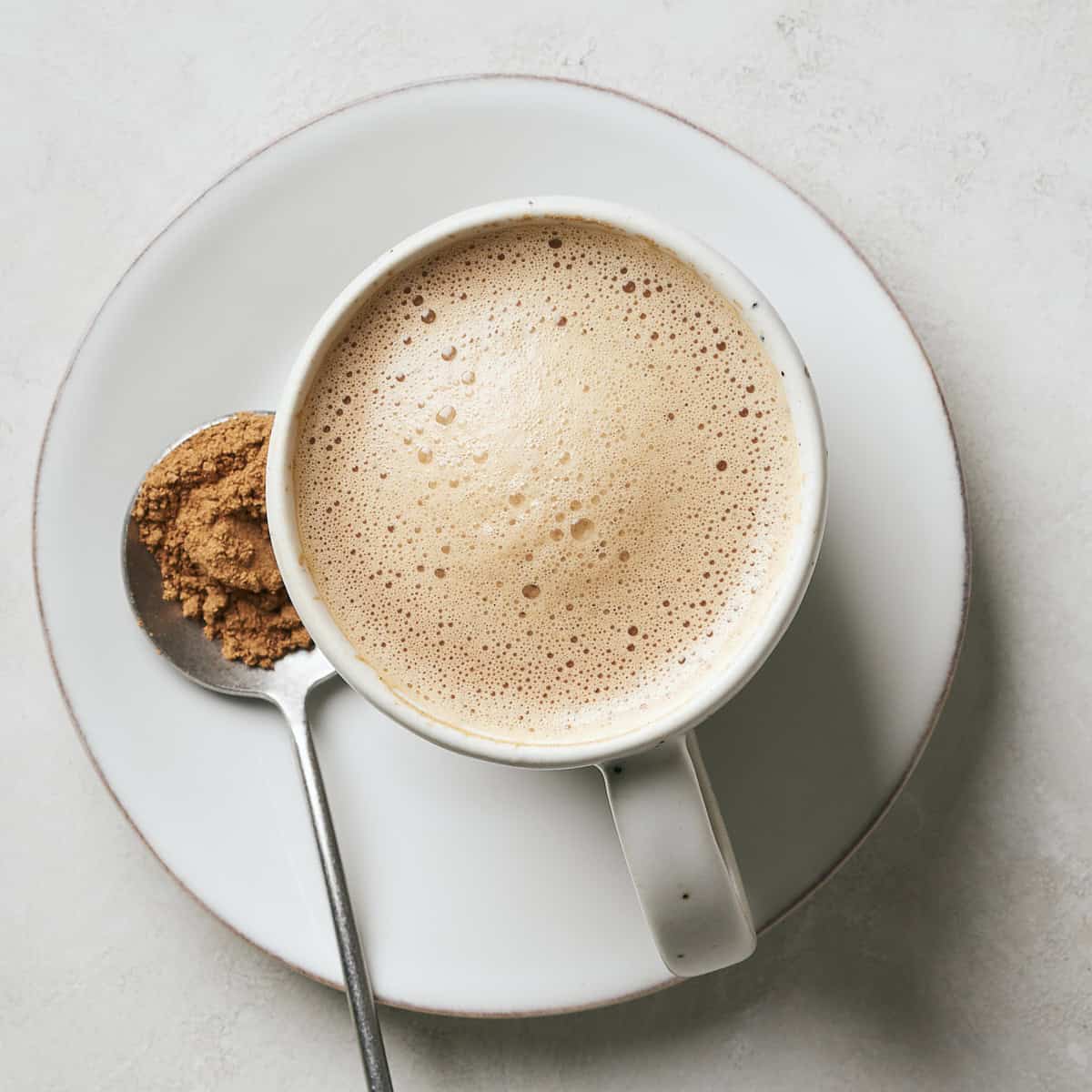 Vegan mushroom latte in a mug with a spoonful of mushroom powder next to it.