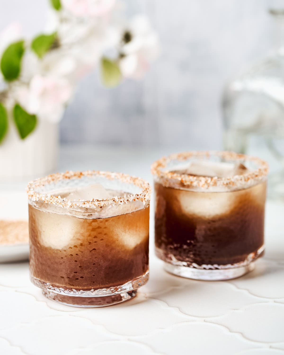 Two glasses filled with tamarind margaritas rimmed with tajin and salt.