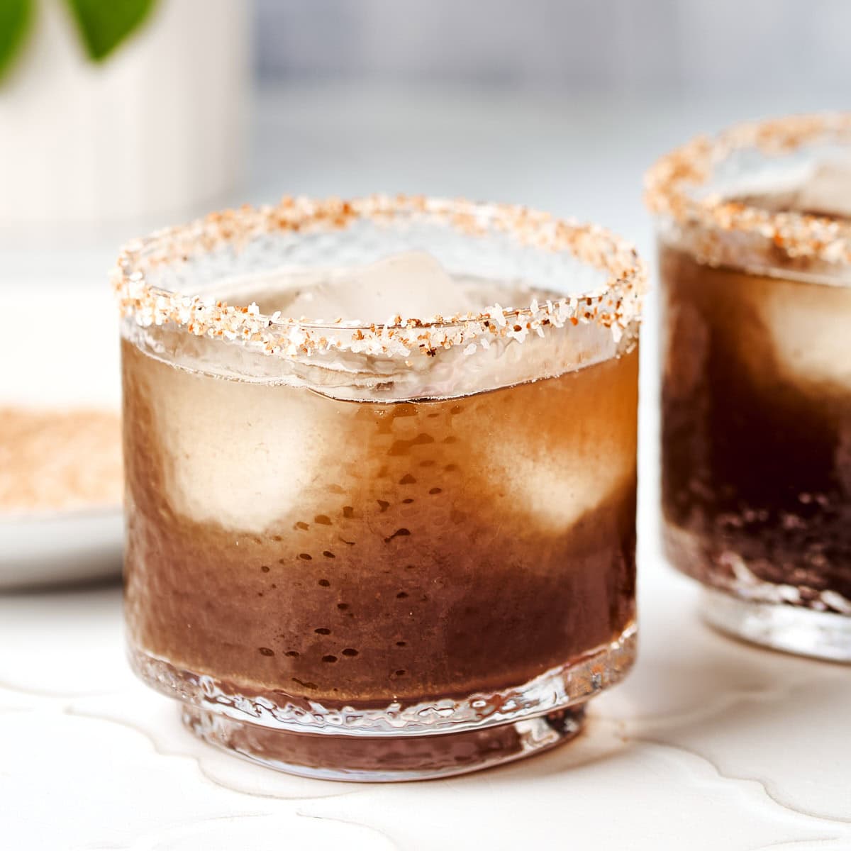 Glass filled with tamarindo margarita rimmed with tajin and salt.