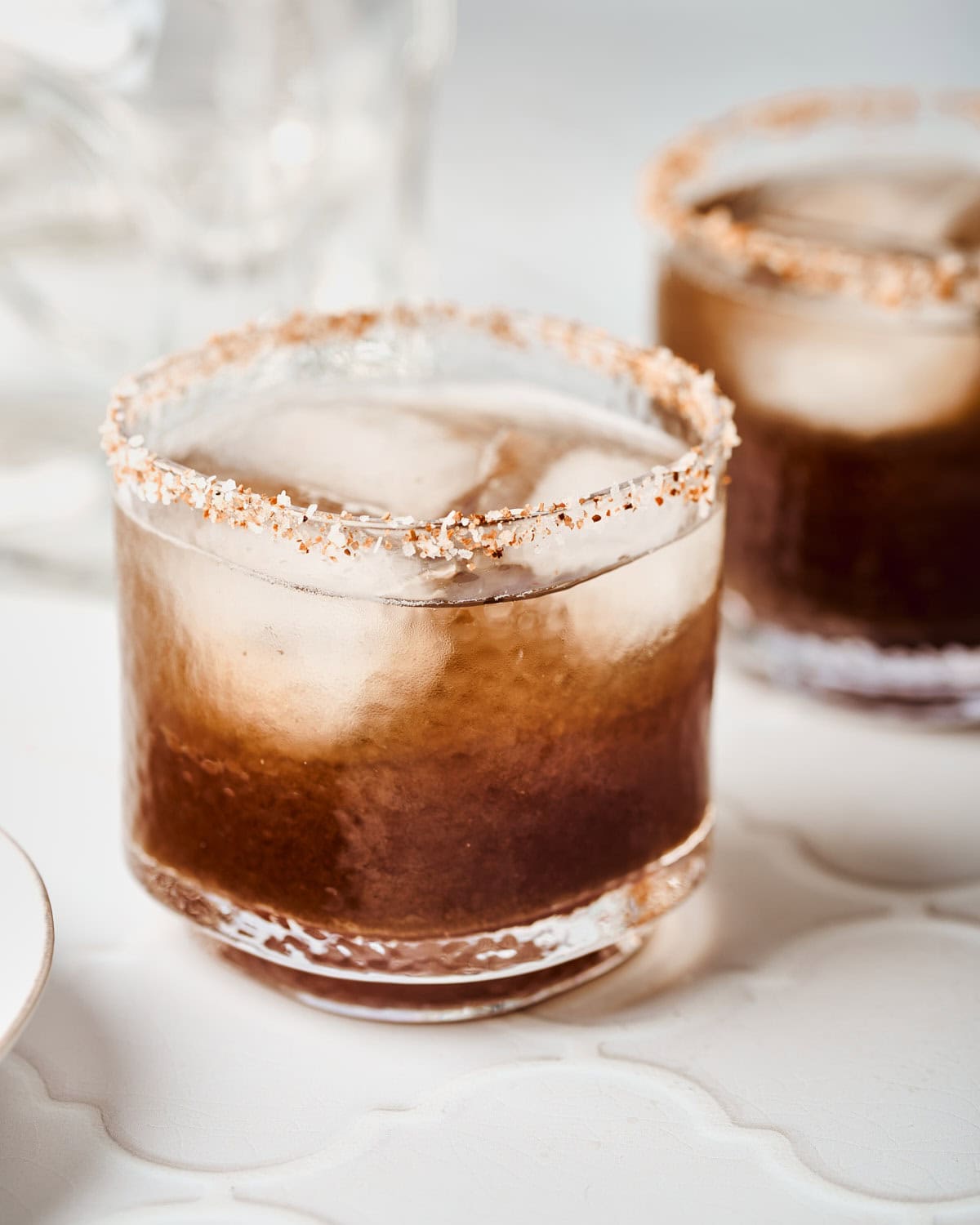 Glass filled with tamarind margarita rimmed with tajin and salt.