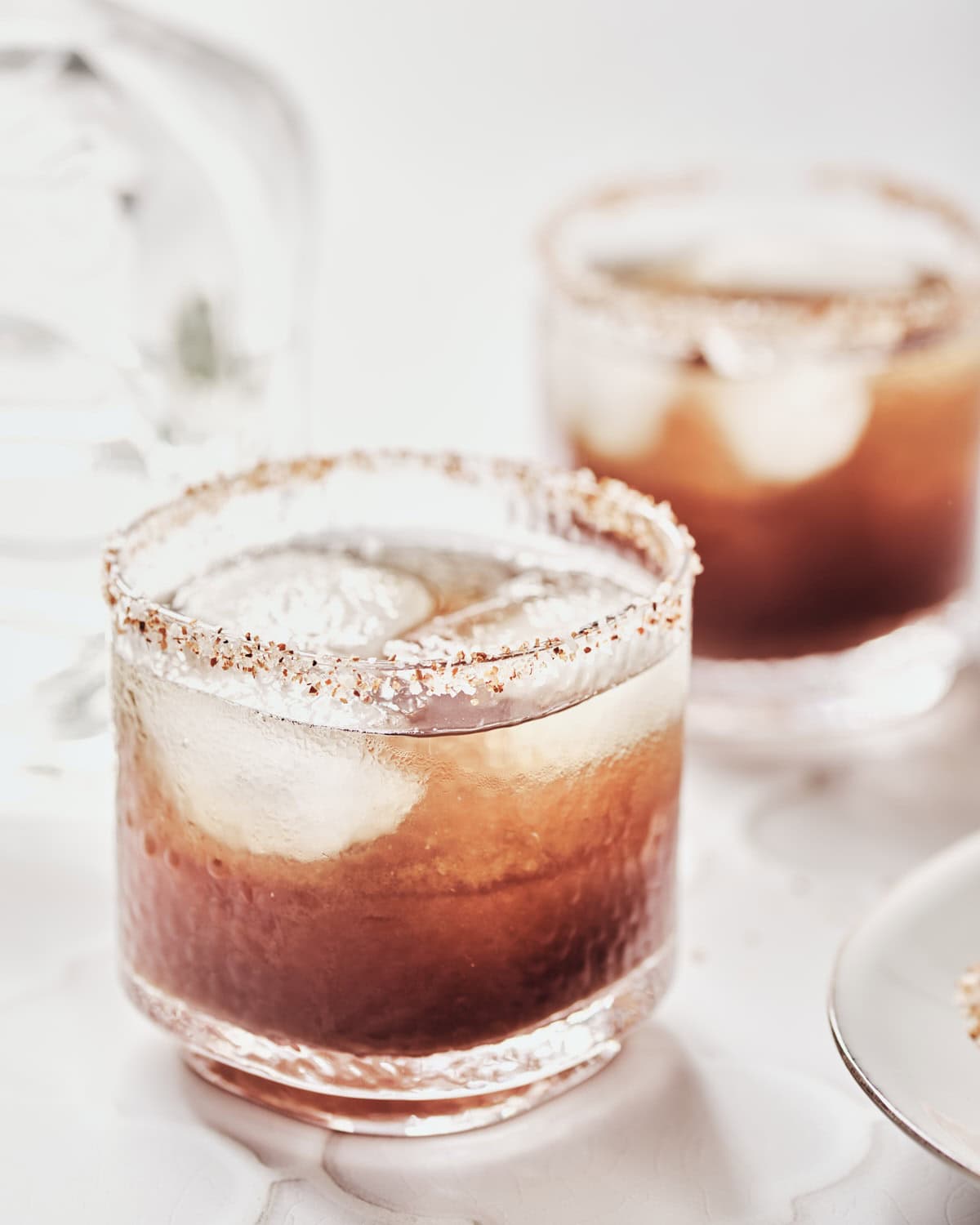 Glass filled with tamarind margarita rimmed with tajin and salt.